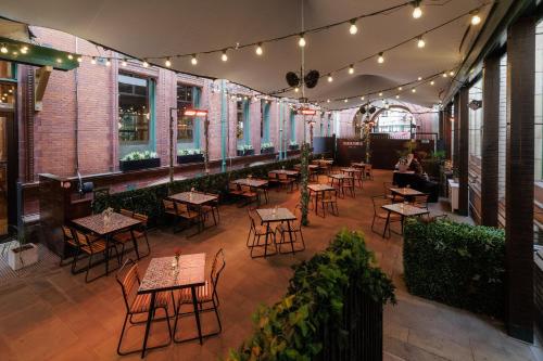 an empty restaurant with tables and chairs and lights at Kimpton Clocktower by IHG in Manchester