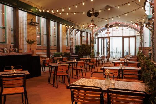 a restaurant with tables and chairs and lights at Kimpton Clocktower by IHG in Manchester