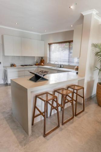 a kitchen with a island with two bar stools at Relax in Style at this Stunning Villa in Camps Bay, Cape Town in Cape Town