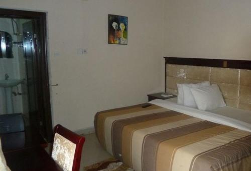 a hotel room with a bed and a chair at Bellwood Hotel - Super Deluxe in Asaba
