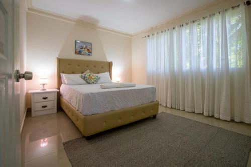 a bedroom with a bed and a window with curtains at Fully Equipped 2br Apt-dt5mins To The Beach in Sosúa