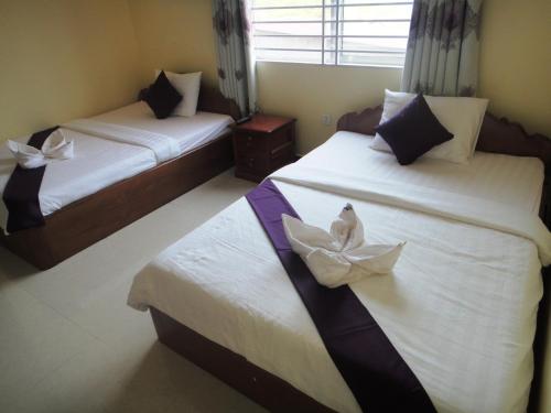 a bedroom with two beds with white flowers on them at Khemra I Guesthouse in Kampot