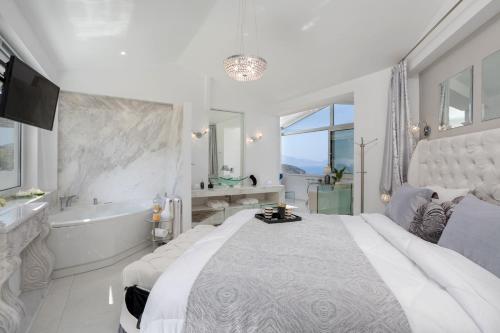 a white bedroom with a large bed and a bath tub at Dion Villa Zakynthos Greece One Bedroom Villa with Private Pool no01 in Agios Nikolaos