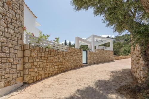 a brick wall with a white gate on top of it at Dion Villa Zakynthos Greece One Bedroom Villa with Private Pool no01 in Agios Nikolaos