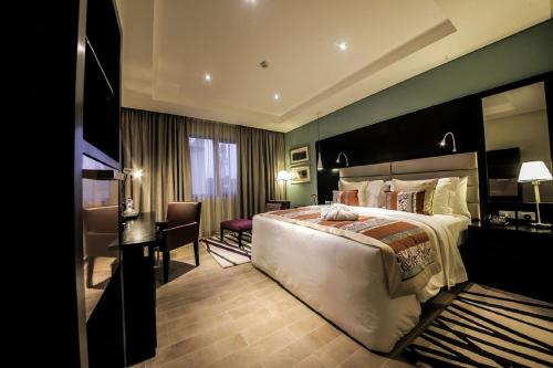 a hotel room with a large bed and a desk at The Providence Hotel by Mantis in Ikeja