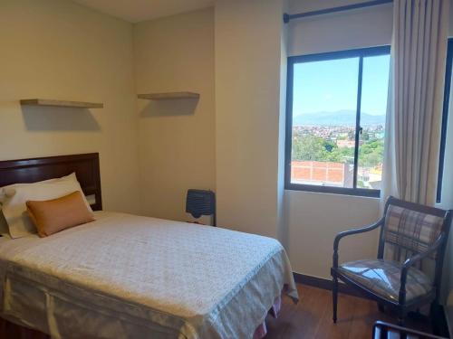 a bedroom with a bed and a window and a chair at Departamento Independencia in Tarija