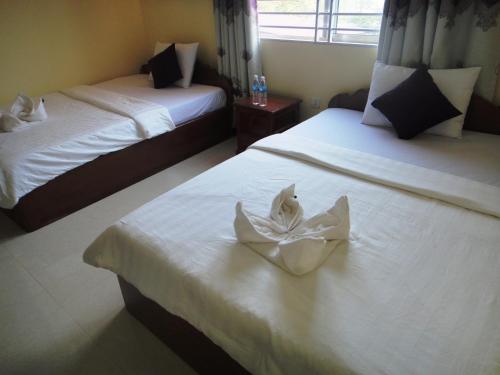 two beds with white towels on top of them at Khemra I Guesthouse in Kampot