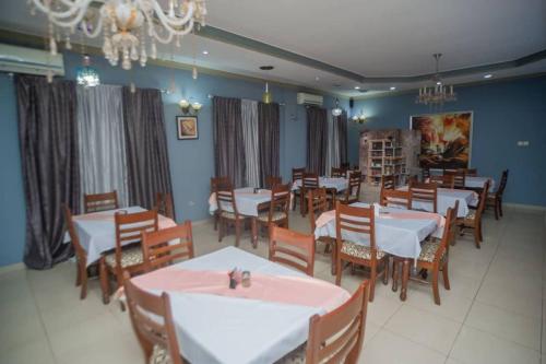 a dining room with tables and chairs and a chandelier at Large Cozy room including free breakfast in Lubumbashi