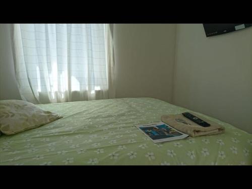 a bed with a book and a remote control on it at Double Room private shower room - deg-yr in Hayes