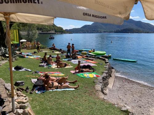 a group of people laying on the grass at a lake at Lago Maggiore Holiday House with Panoramic Views in Dumenza