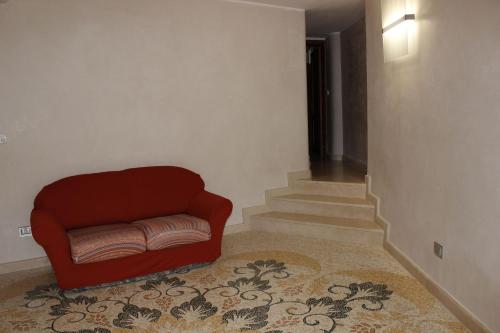 a living room with a red chair and stairs at Palazzo De Donno App no04 in Santa Cesarea Terme