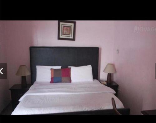 a bedroom with a bed with a black headboard and two lamps at Christine Hotel - Christine Monarch in Port Harcourt