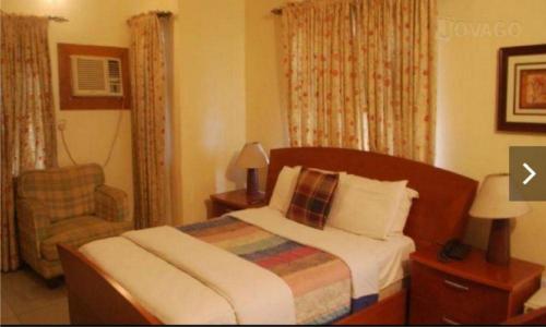 a hotel room with a bed and a chair at Christine Hotel - Christine Monarch in Port Harcourt