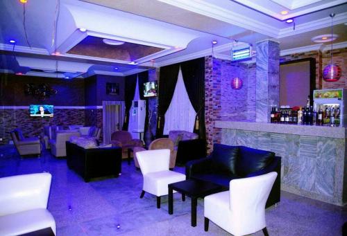 a room with a bar with white chairs and tables at Hampton Towers Spa - Deluxe Twin in Asaba