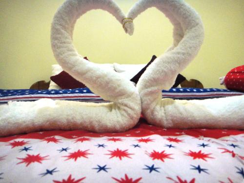 two swans shaped like hearts sitting on a bed at Khemra I Guesthouse in Kampot