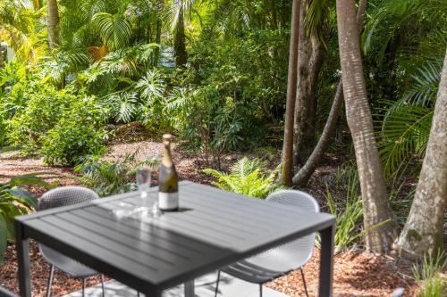a bottle of wine sitting on a table with chairs at Elvis - The Great Seaside Escape - Luxury Stay in Coffs Harbour