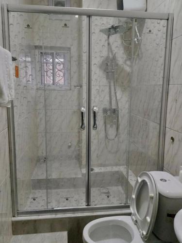 a bathroom with a shower with a toilet and a sink at Blooms Spot Hotel - Super Deluxe in Port Harcourt