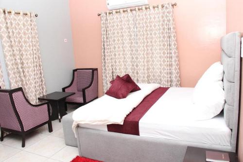 a bedroom with a bed and two chairs at Blooms Spot Hotel - Super Deluxe in Port Harcourt