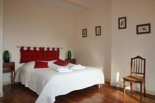 a bedroom with a white bed with red pillows and a chair at La maison de Léonard, Aux grilles du Château de Saint-Aignan, à 2km de Beauval in Saint-Aignan