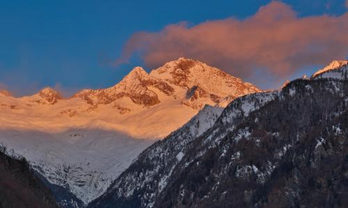 a snow covered mountain range with a cloudy sky at Rifugio Luna Nascente in San Martino
