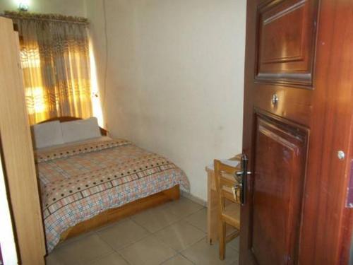 a small bedroom with a bed and a wooden door at Bahamas Hotels International in Abuja