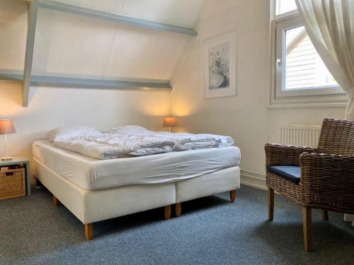 a bedroom with a bed and a window and a chair at Holiday house Viktoria at lake Lauwersmeer in Anjum