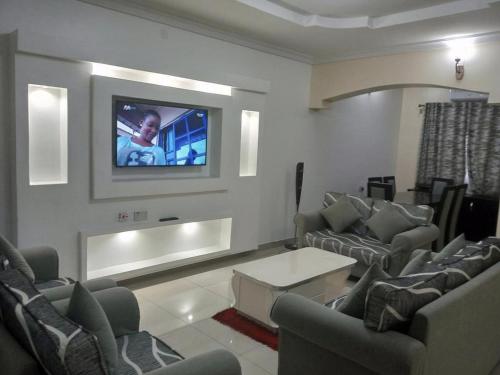 sala de estar con sofás y TV en la pared en Blooms Spot Hotel - Self Service Apartment, en Port Harcourt