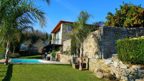 a house with a swimming pool next to a stone wall at Quinta de Padreiro in Arcos de Valdevez