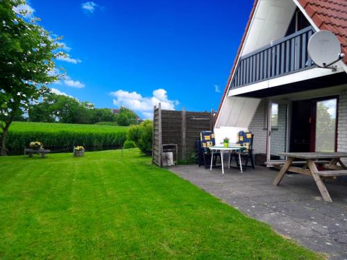 a patio with a table and chairs in a yard at Leonie 6 pers holiday home with a large garden close to the Lauwersmeer in Anjum