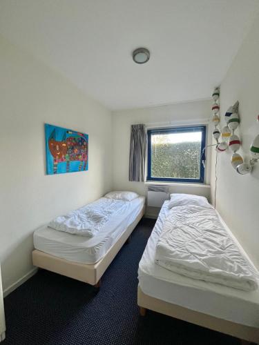 two twin beds in a room with a window at 6pers Modern harbor house Jasmijn with fenced garden and lake view in Anjum