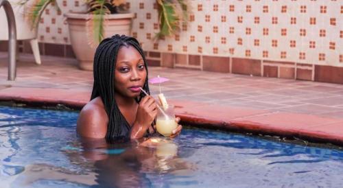 a woman in a swimming pool holding a drink at Apartment Royale Hotel-3 Bd Apartment in Ikeja