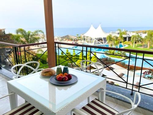 a white table with a plate of fruit on a balcony at Luxurious Seafront Penthouse in Kérynia