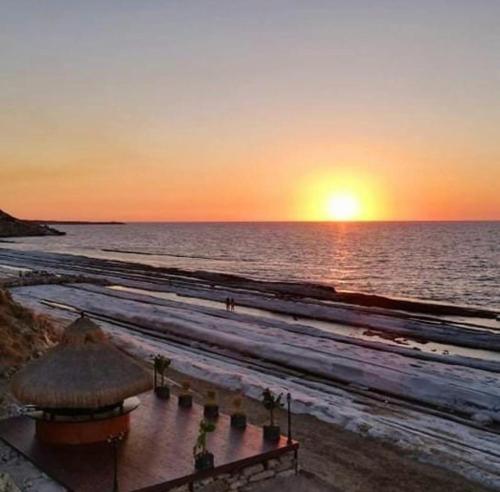 a sunset on a beach with the sun setting over the ocean at Luxurious Seafront Penthouse in Kérynia
