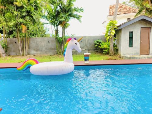 a unicorn float in a swimming pool with a drink at Port Dikson Beach Side Villa in Port Dickson