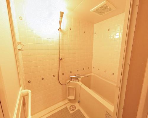 a bathroom with a shower with a tub and a toilet at The Global West in Niihama