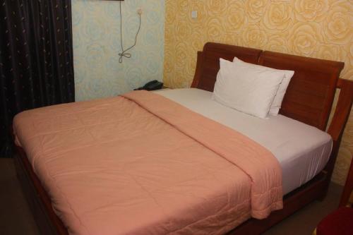 a bed with an orange blanket and a white pillow at Owees Place-standard in Lagos