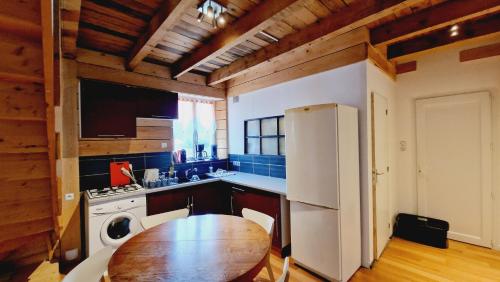 une cuisine avec une table et un réfrigérateur blanc dans l'établissement F3 Duplex Fresse, à Fresse-sur-Moselle