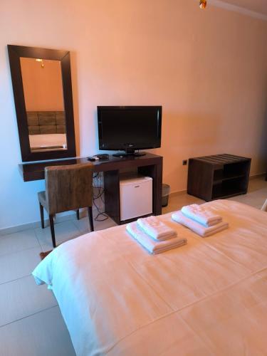 a bedroom with a bed with a desk and a television at Faraggi Hotel in Simvolí