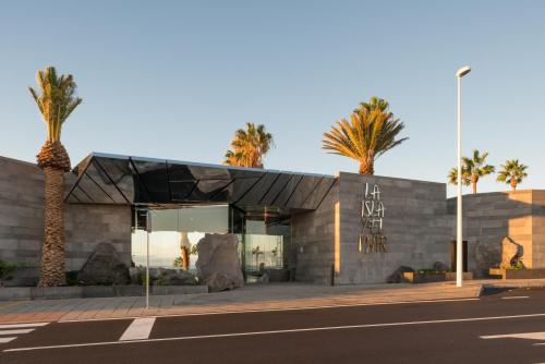 a building with palm trees in front of it at La Isla y el Mar, Hotel Boutique in Puerto del Carmen