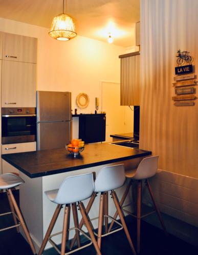 une cuisine avec un îlot et des tabourets de bar dans l'établissement Le Charme d'Arnaud Hypercentre Wifi Accueil gratuit h24, à Toulouse