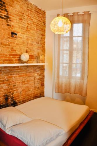 un lit dans une chambre avec un mur de briques dans l'établissement Le Charme d'Arnaud Hypercentre Wifi Accueil gratuit h24, à Toulouse