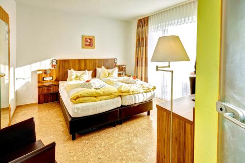 ein Schlafzimmer mit einem Bett, einem Schreibtisch und einer Lampe in der Unterkunft Hotel Muschinsky in Bad Lauterberg