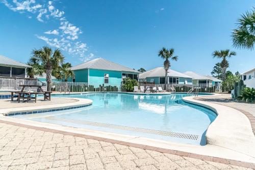 a swimming pool with palm trees and houses at 4014 Rookery 3 Cottage with two Pools and Beach Amenities in Gulf Highlands