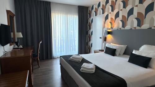 a hotel room with a large bed and a desk at Hotel Le Bourgogne in Évian-les-Bains