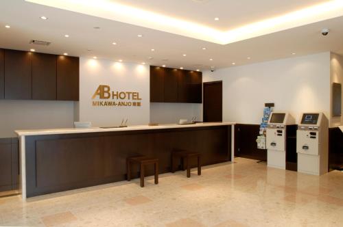 a kitchen with a counter and stools in a building at AB Hotel Mikawa Anjo Minamikan in Anjo
