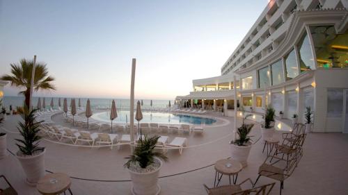 a hotel with a pool and chairs and tables and the ocean at ON Hotels Oceanfront Adults Designed in Matalascañas