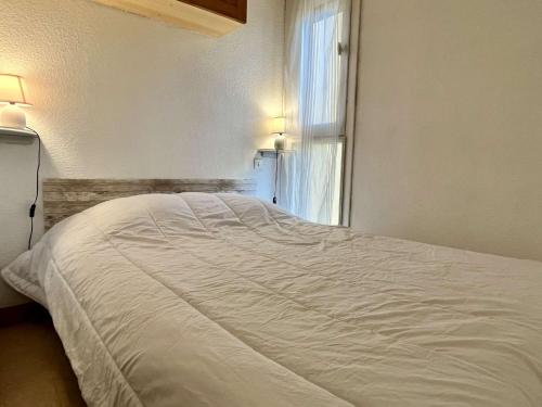 un lit blanc dans une chambre avec une fenêtre dans l'établissement Appartement Studio 4 couchages ARGELES SUR MER AR070-2037, à Argelès-sur-Mer