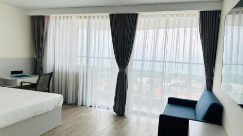 a bedroom with a bed and a chair and a window at Apec Sun Condotel Tuy Hoà - Sea View in Phước Hậu