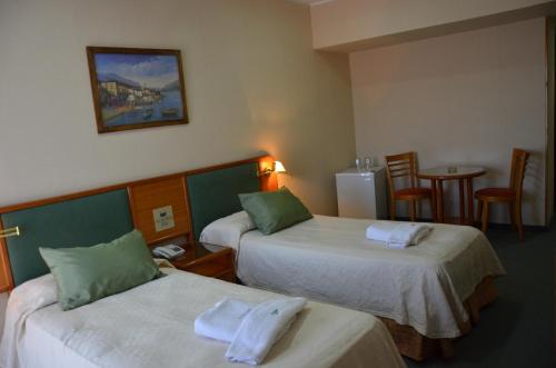 Habitación de hotel con 2 camas y mesa en Hotel Algeciras en Pinamar