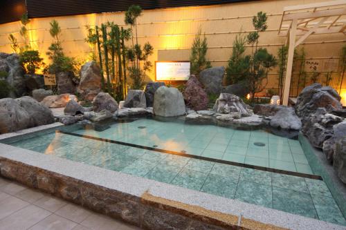 a swimming pool with rocks in a building at -SPA RESORT- Nagoya Kasadera Hotel in Nagoya